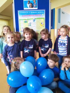 Dzieci z grupy II, ubrane na niebiesko pozują na tle tablicy dotyczącej Konwencji o Prawach Dziecka