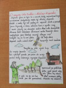 Na zdjęciu pierwszym znajduje się tytuł, treść legendy oraz ilustracje związane z nią tematycznie, wykonane przez dzieci.  Ilustracja przedstawia  postać Mikołaja Kopernika, Orła Bielika oraz olsztyński zamek.