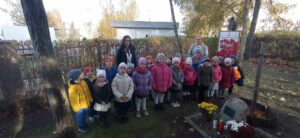 Zdjęcie przedstawia grupę dzieci przedszkolnych wraz dwiema nauczycielkami przy Dębie Katyńskim