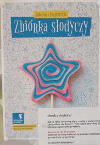 Zdjęcie przedstawia plakat, na którym jest kolorowy lizak w kształcie gwiazdy oraz treść ogłoszenia dla rodziców o zbiórce słodyczy.