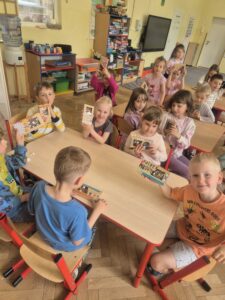Zdjęcie przedstawia uśmiechniętą grupę dzieci z tabliczkami czekolady.