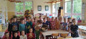 Na zdjęciu widać grupę dzieci. na środku zdjęcia dwoje dzieci trzyma garnek, w którym są pokrojone na kompot owoce