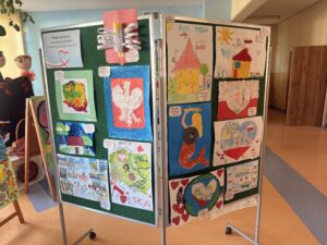 na fotografii widać tablice, na których znajdują się prace plastyczne, które wzięły udział w konkursie plastycznym. Na pracach znajdują się obrazy o treści patriotycznej: polskie symbole narodowe, polskie krajobrazy