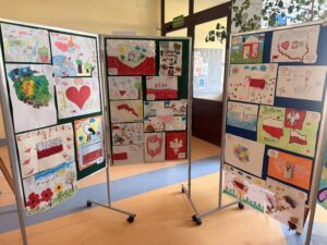 na fotografii widać tablice, na których znajdują się prace plastyczne, które wzięły udział w konkursie plastycznym. Na pracach znajdują się obrazy o treści patriotycznej: polskie symbole narodowe, polskie krajobrazy