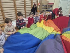 Zdjęcie przedstawia dzieci bawiące się chustą animacyjną