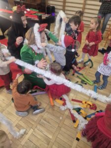 Zdjęcia przedstawia dzieci ubierające panią choinkę