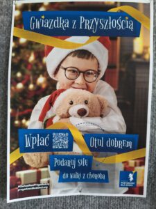 Na zdjęciu chłopiec siedzący w czapce Mikołajowej. Dziecko ma okulary i trzyma misia.