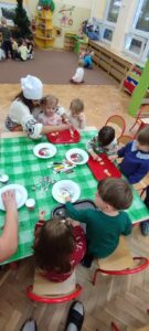 Zdjęcie przedstawia dzieci dekorujące ciasteczka lukrami i posypkami,